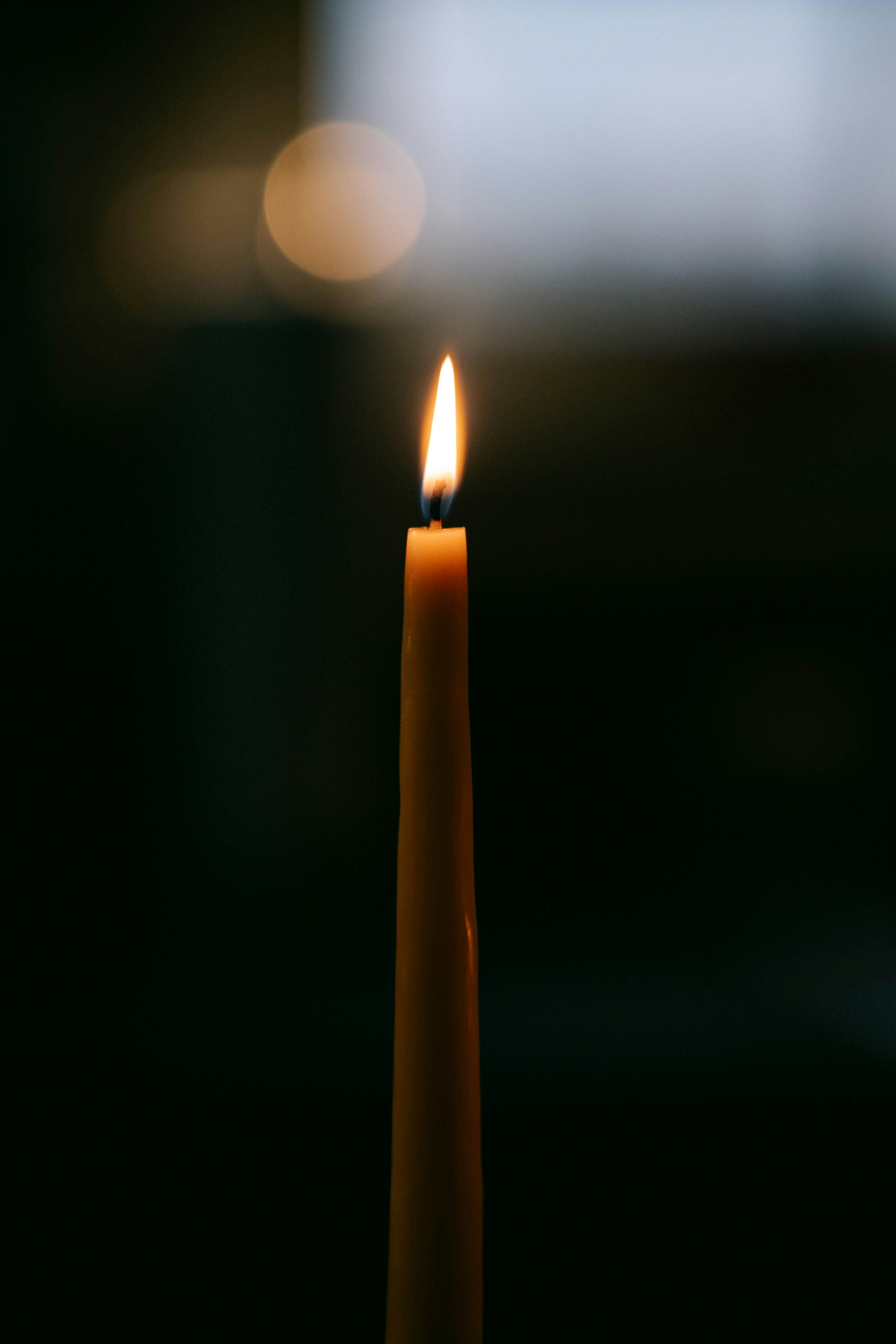A single candle is lit in the dark