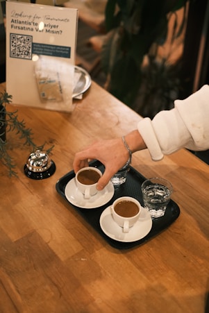 A person pouring coffee into two cups on a table