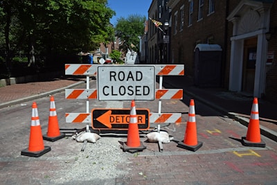 A road closed sign surrounded by orange traffic cones