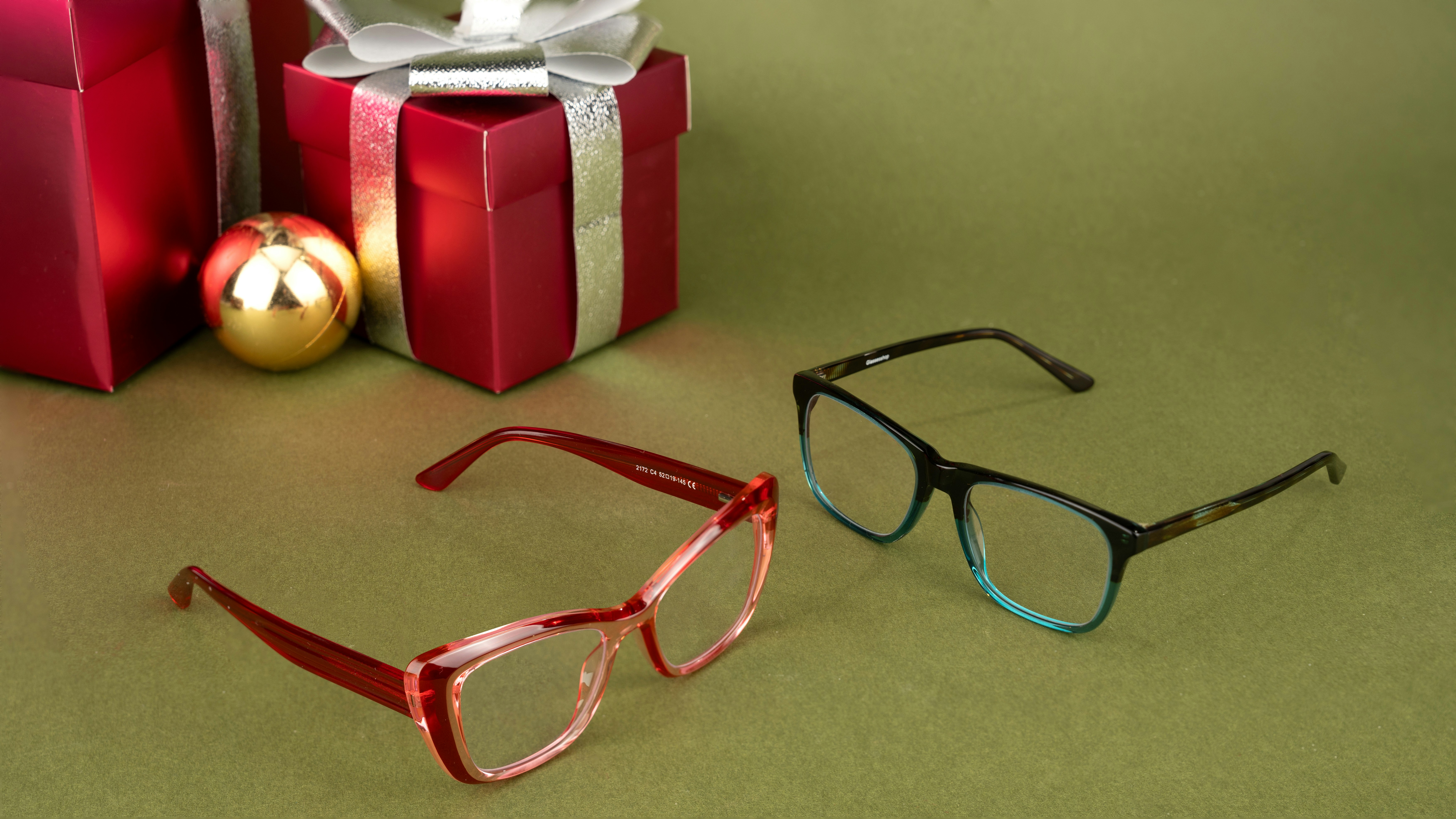 Perfect for gifting, these glasses sit stylishly beside beautifully wrapped red gift boxes adorned with shimmering silver ribbons and a golden ornament. Whether you're looking to refresh your look or surprise someone special, these frames combine style and functionality, making them an ideal choice for the holiday season.