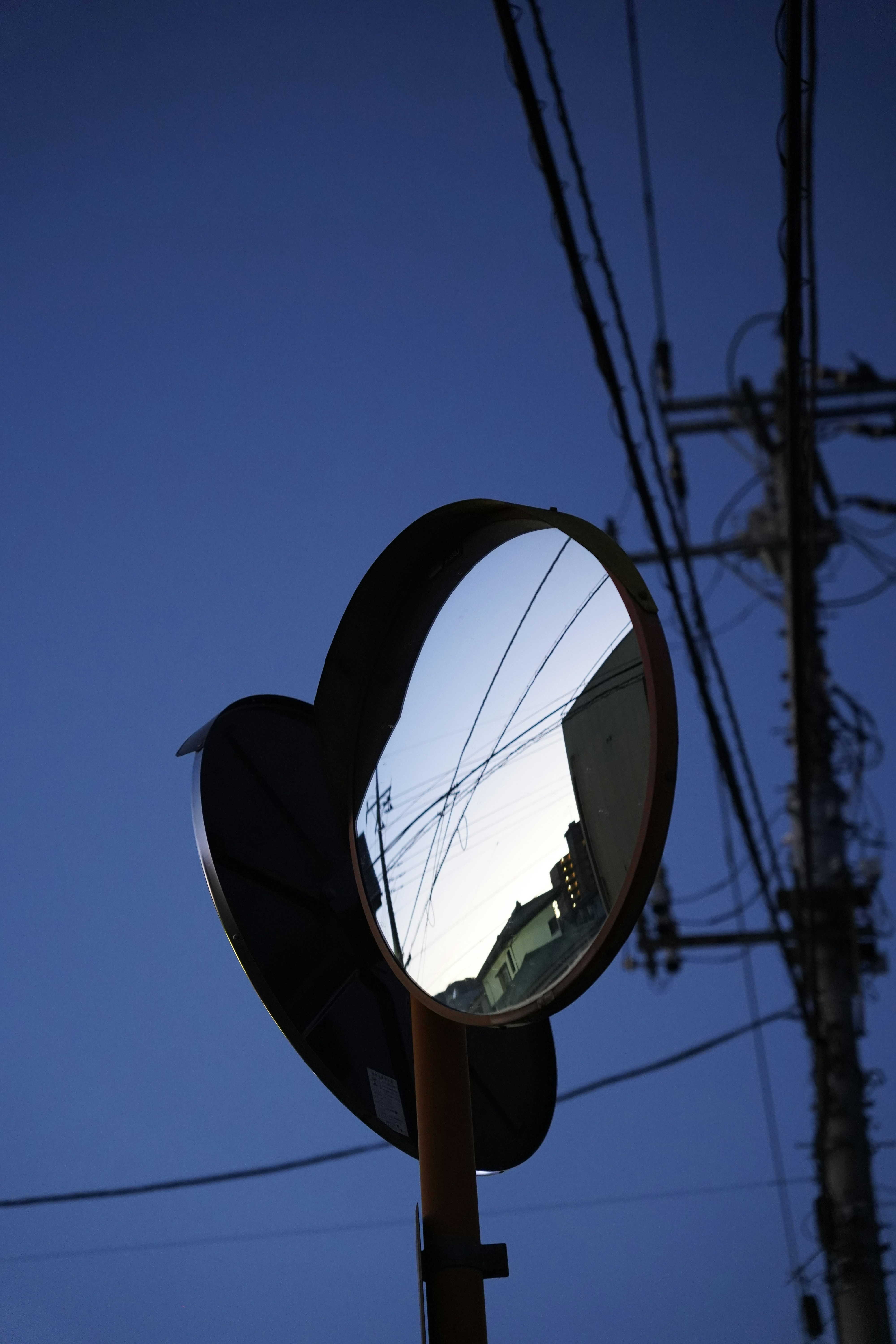 A round mirror on a pole with power lines in the background