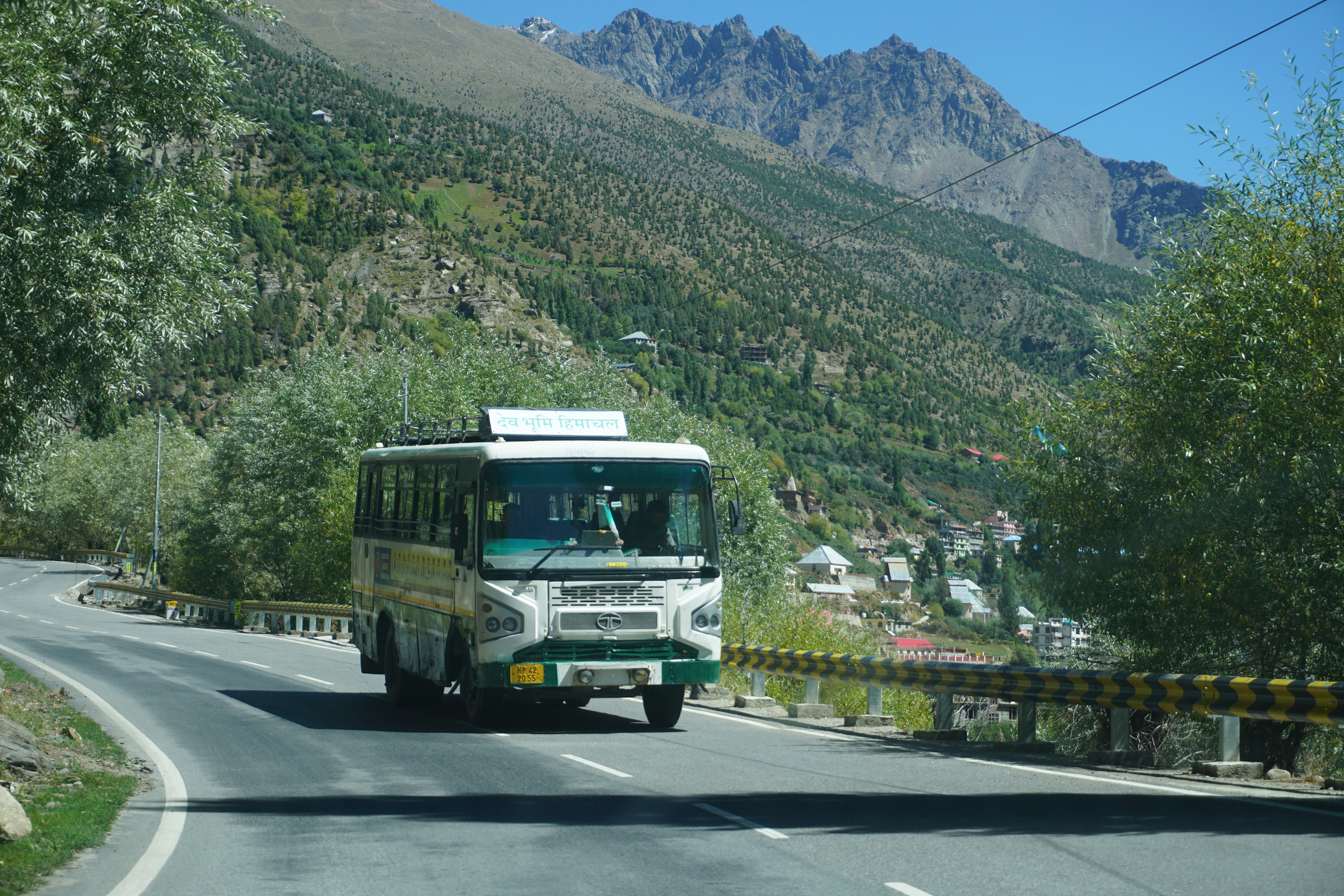 A bus driving down a road with mountains in the background