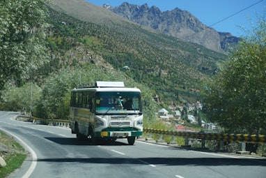A bus driving down a road with mountains in the background