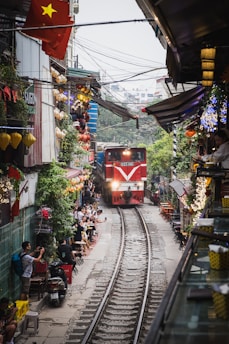 A red train traveling down train tracks next to a crowd of people