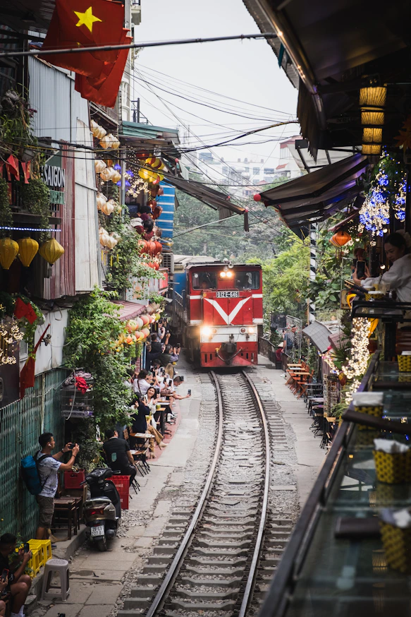 A red train traveling down train tracks next to a crowd of people