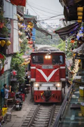 A red train traveling down train tracks next to a building
