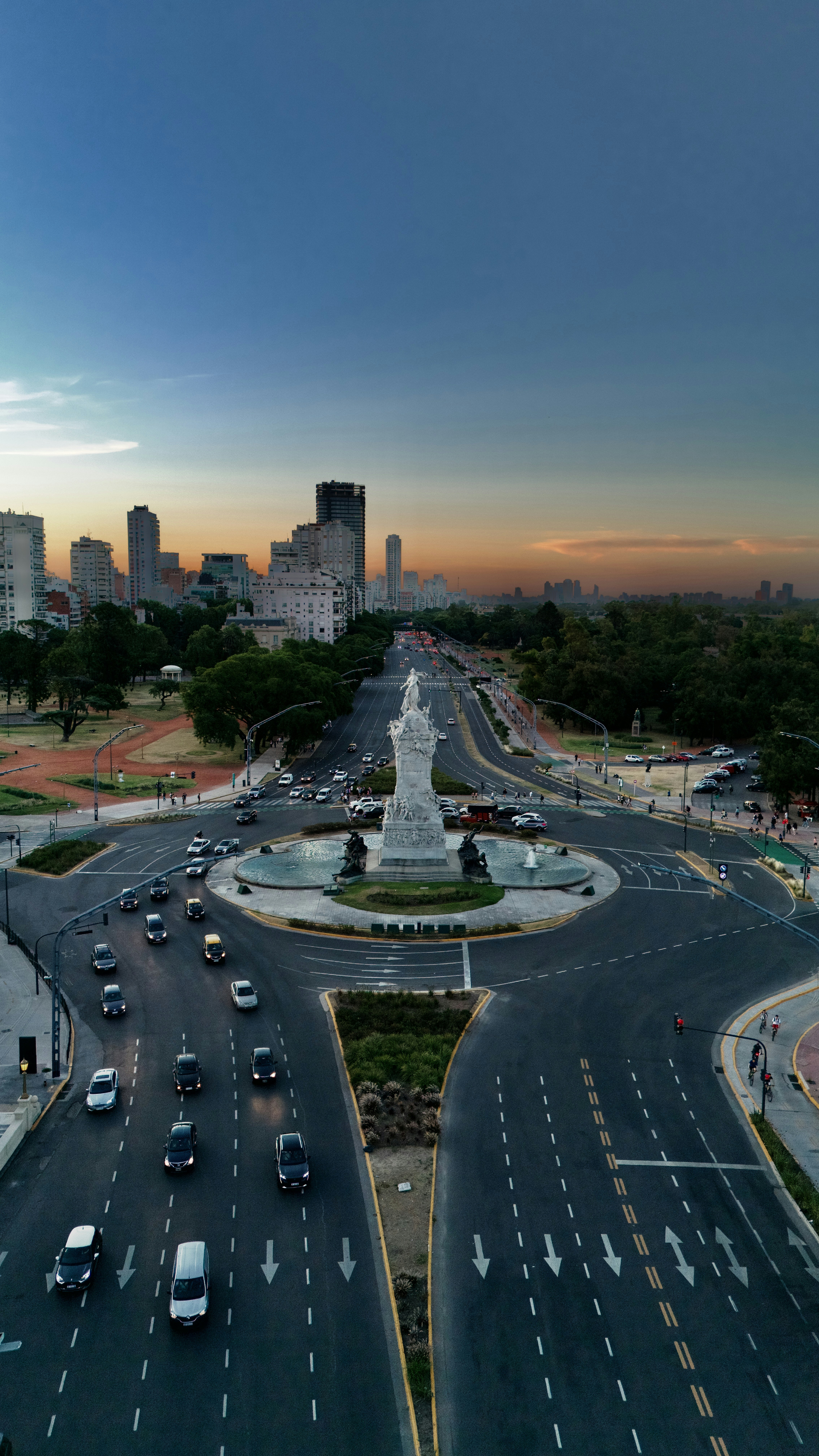 An aerial view of a city street with a fountain in the middle