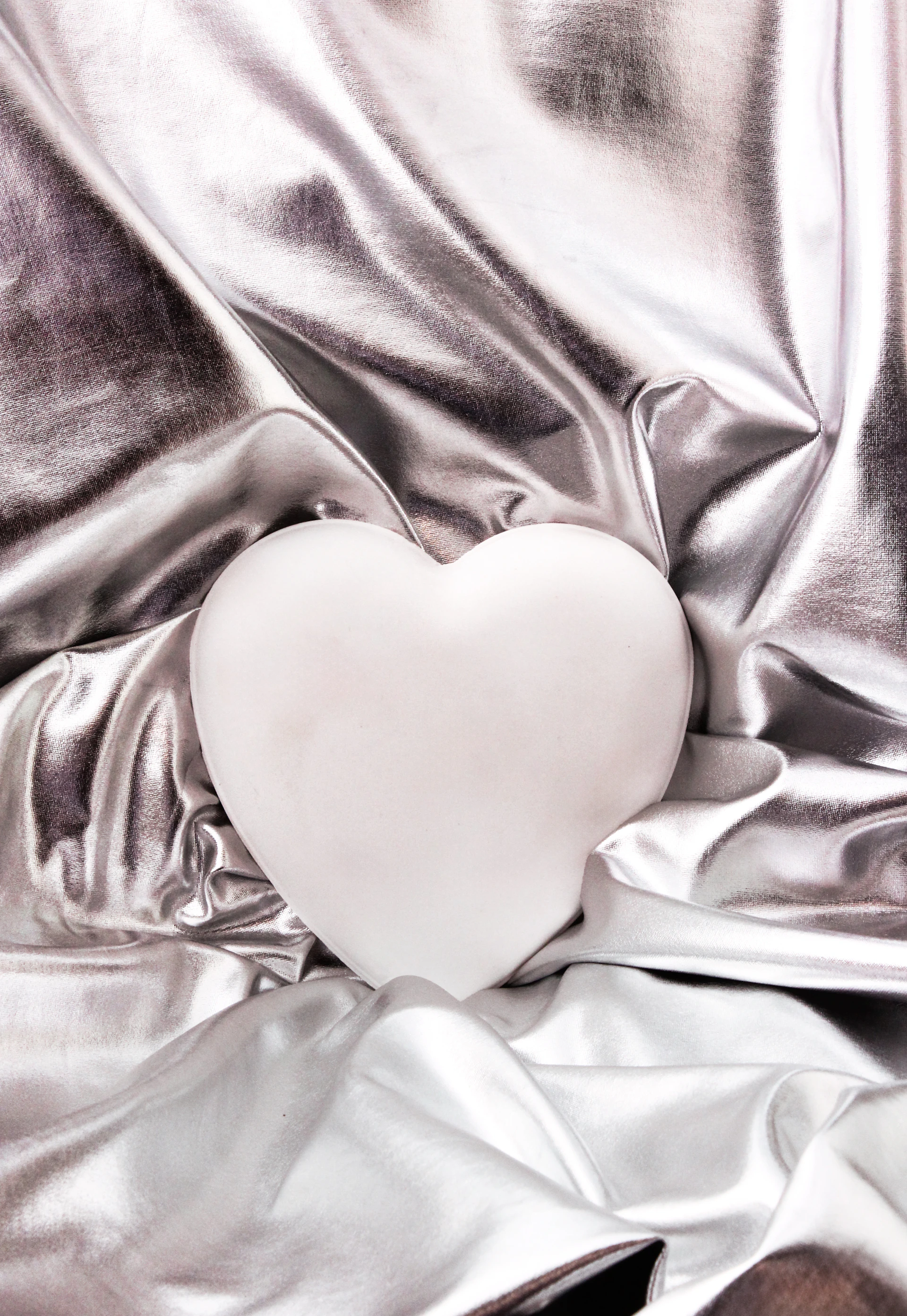 A white heart sitting on top of a silver cloth