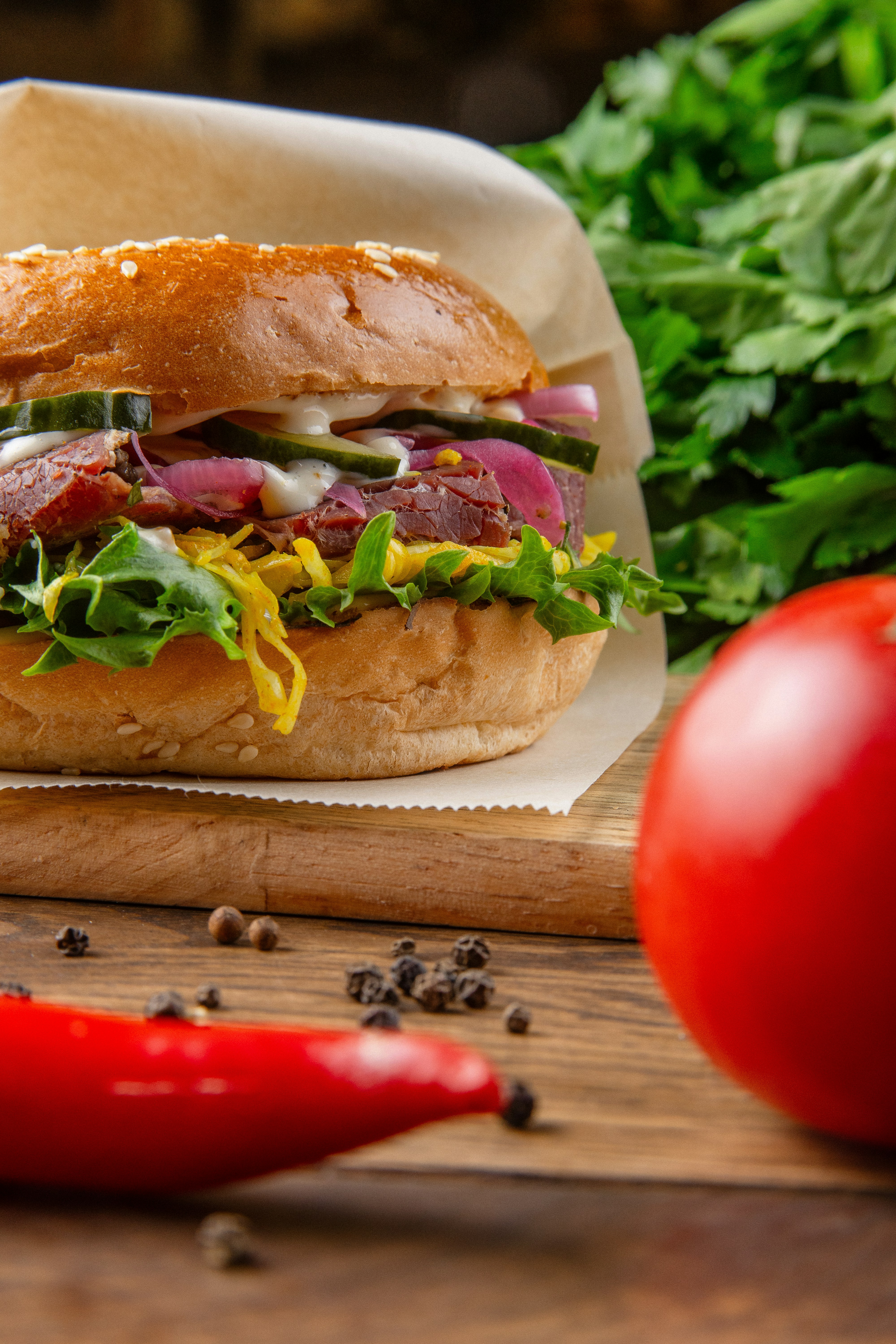 A sandwich with meat and vegetables on a cutting board