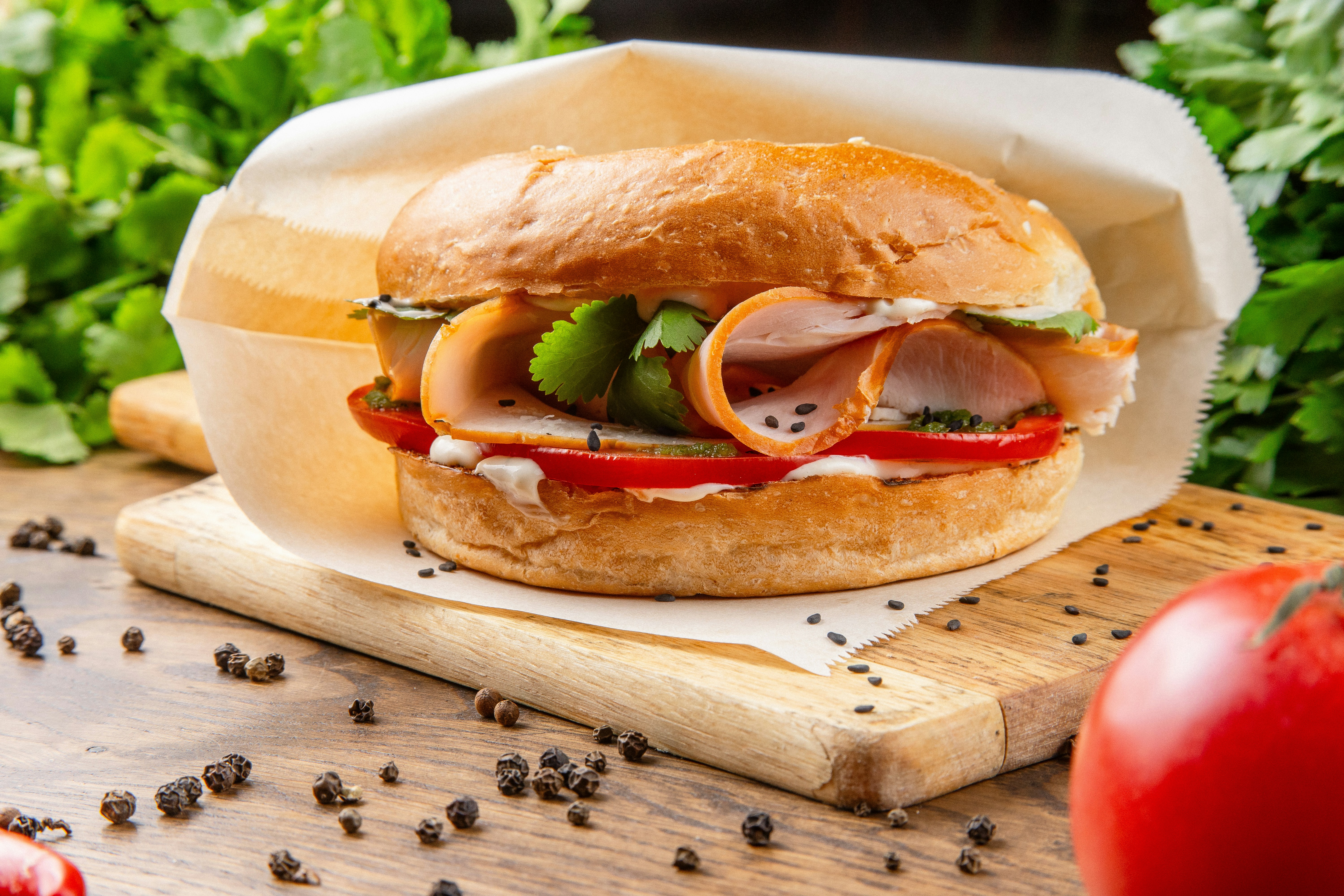A sandwich with meat and vegetables on a cutting board