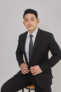 A man in a suit sitting on a stool