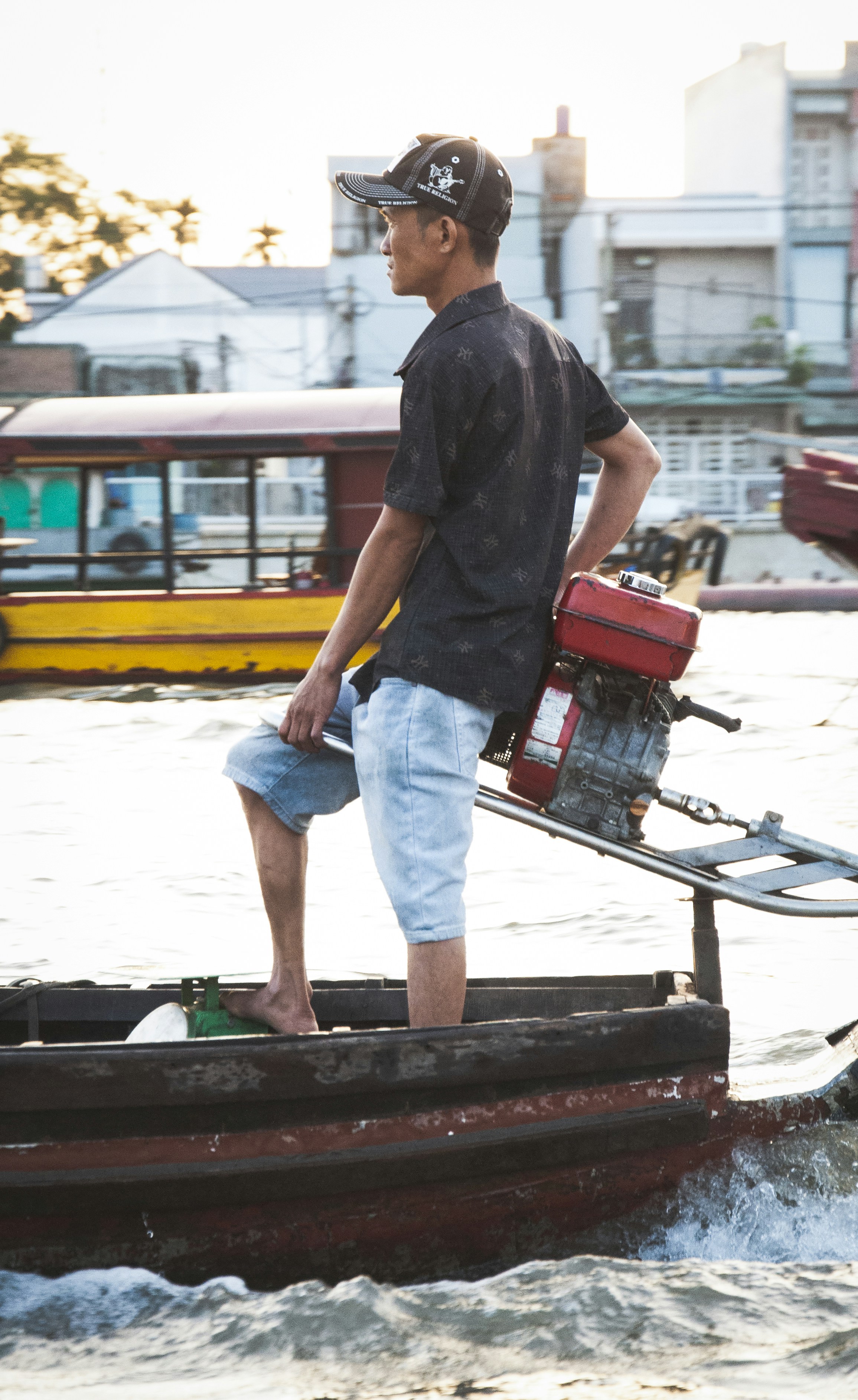 A man standing on the back of a boat in the water