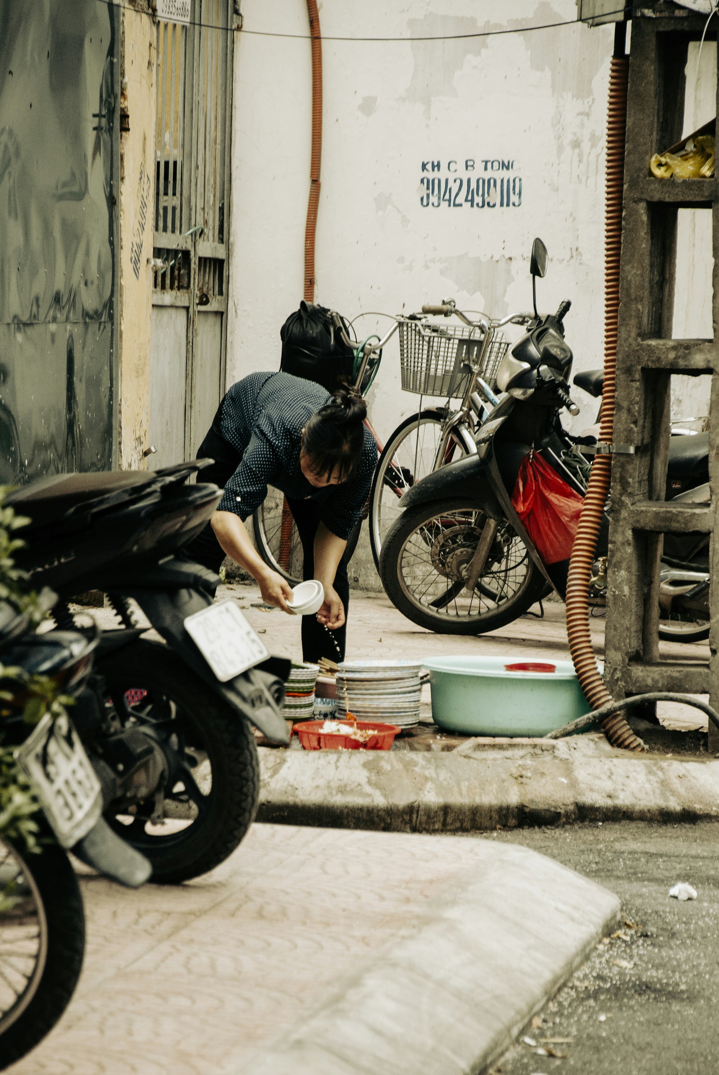 A woman is washing dishes on the street
