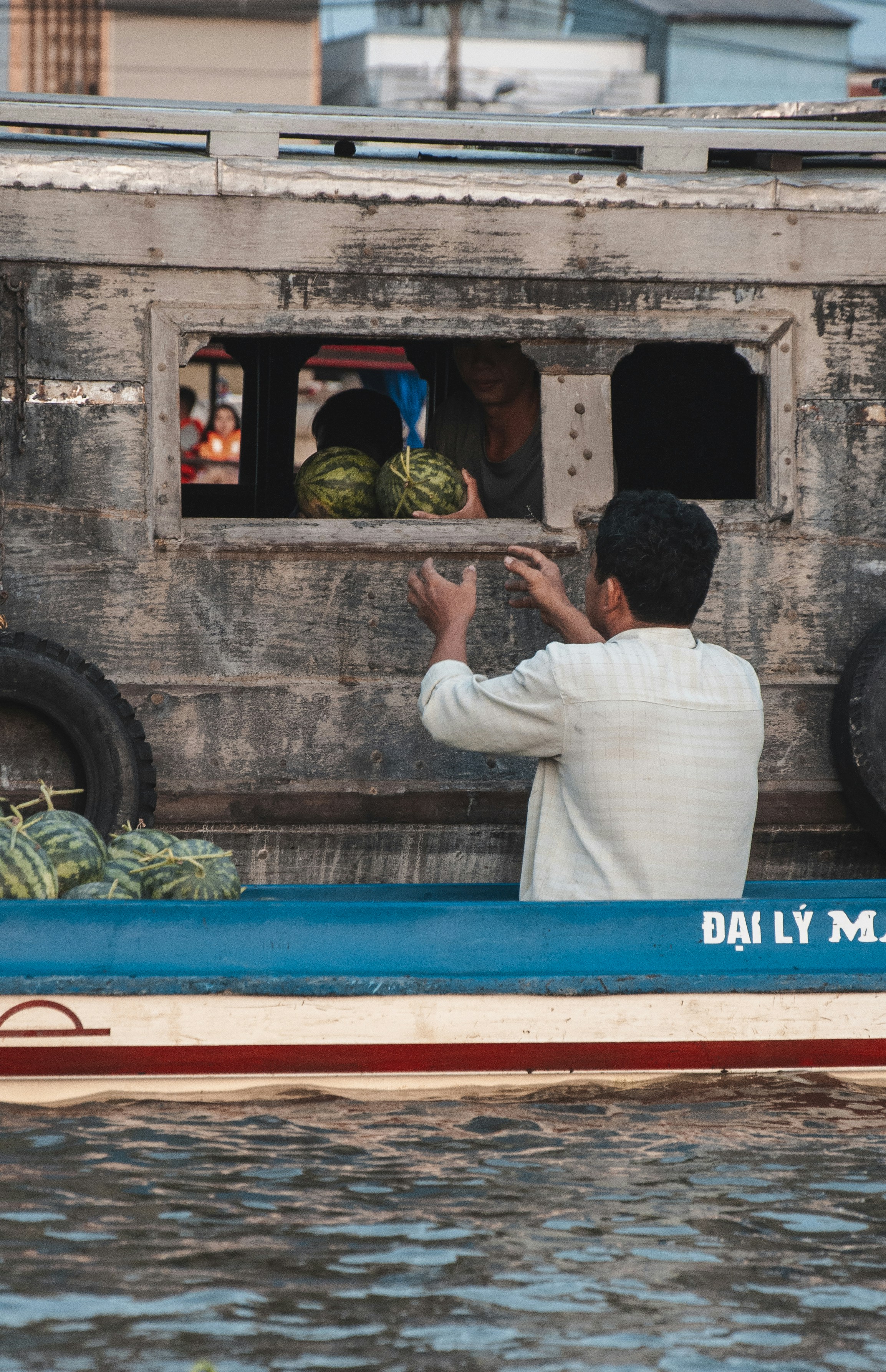 A man on a boat with a bunch of watermelons