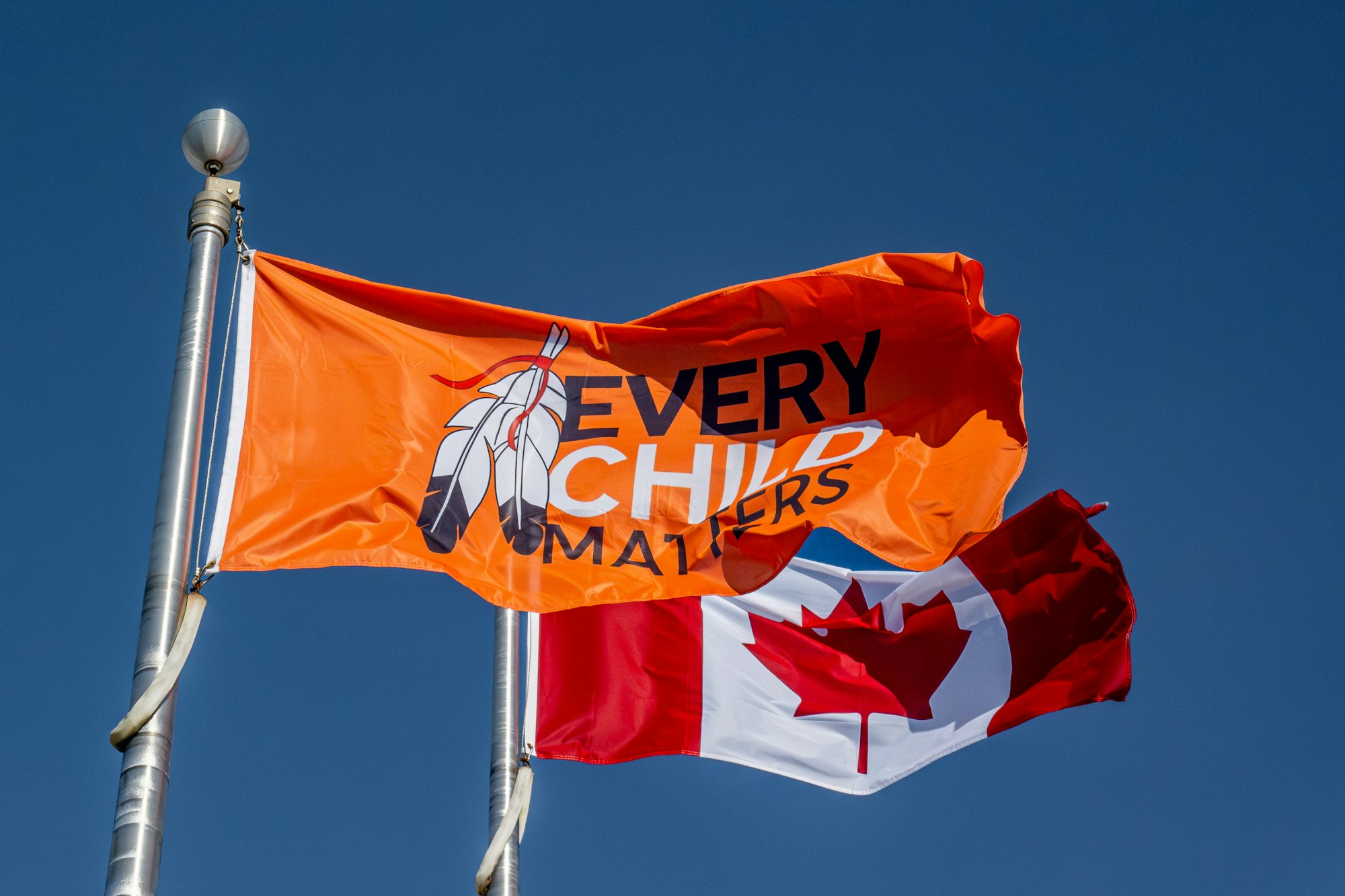 Two flags flying in the wind on a sunny day