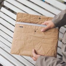 A person sitting on a bench holding a brown bag