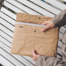 A person sitting on a bench holding a brown bag