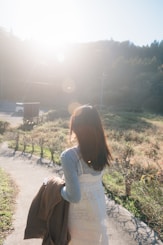A woman walking down a path carrying a brown bag