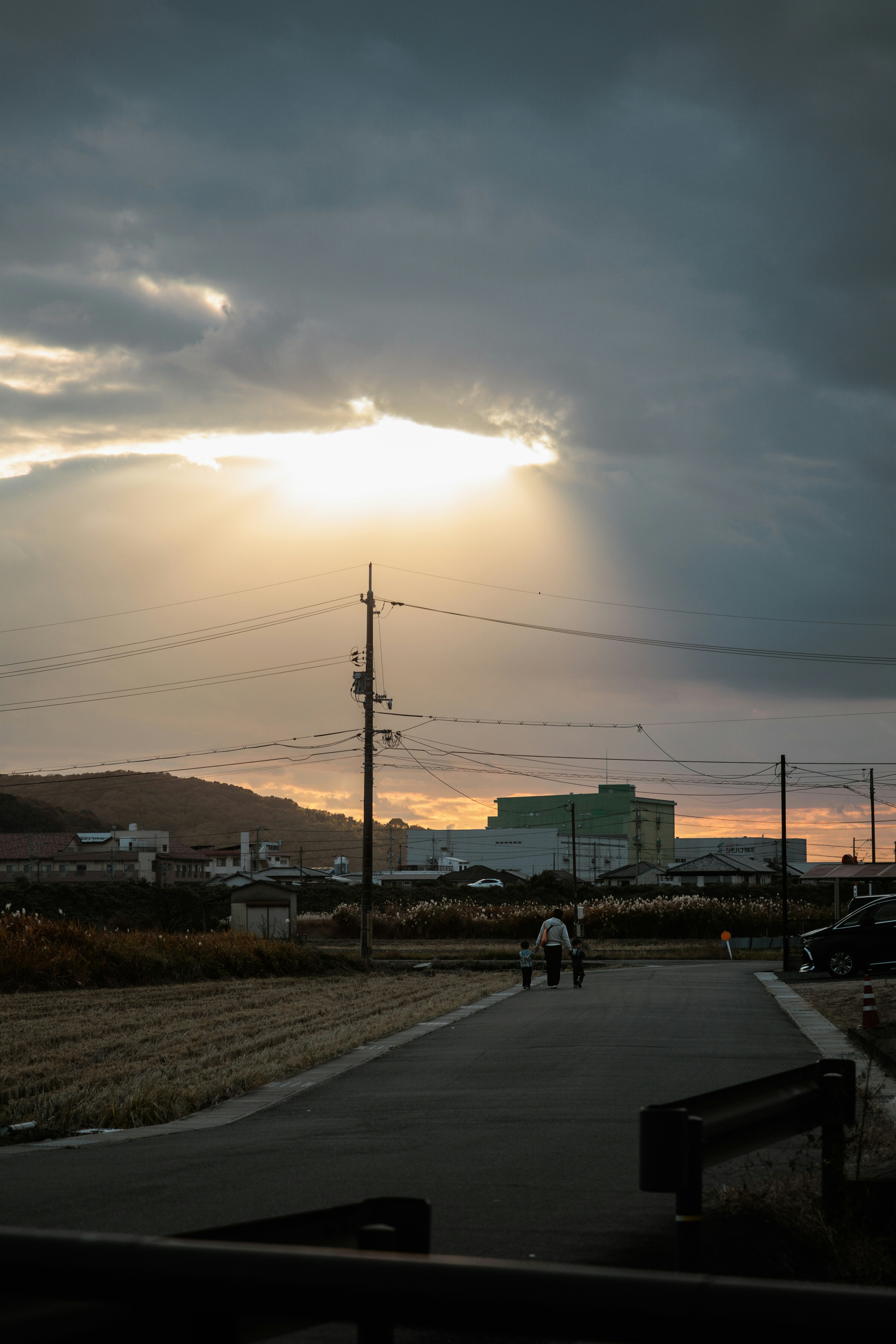 A person walking down a road under a cloudy sky