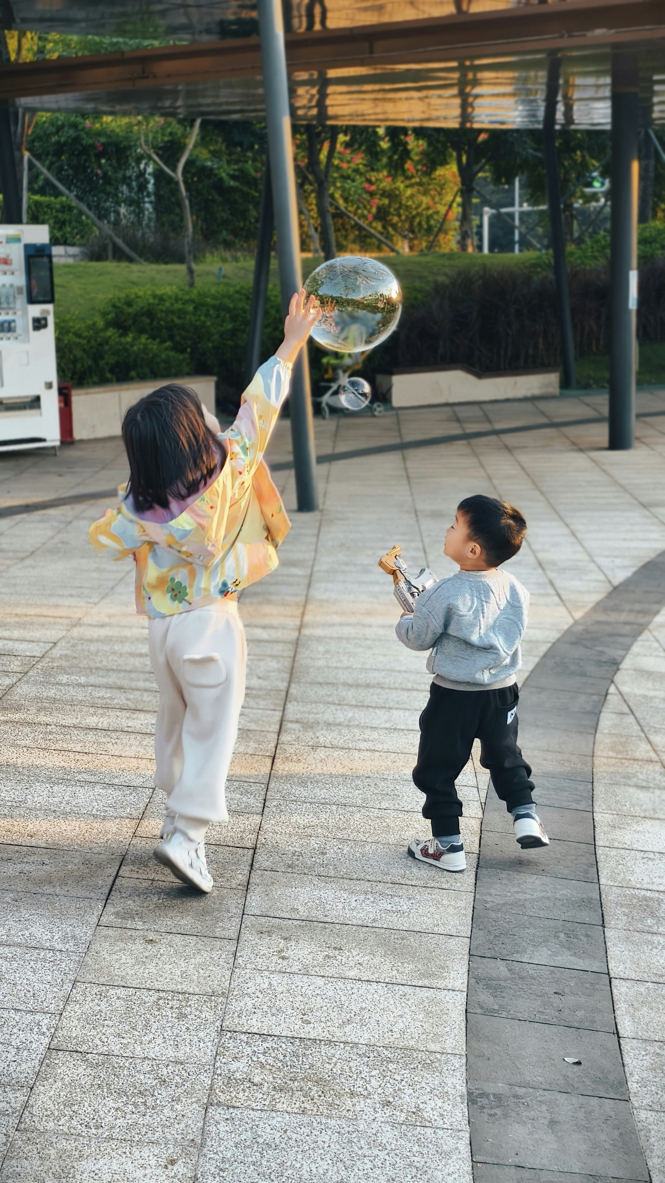 Two children playing with bubbles in a park