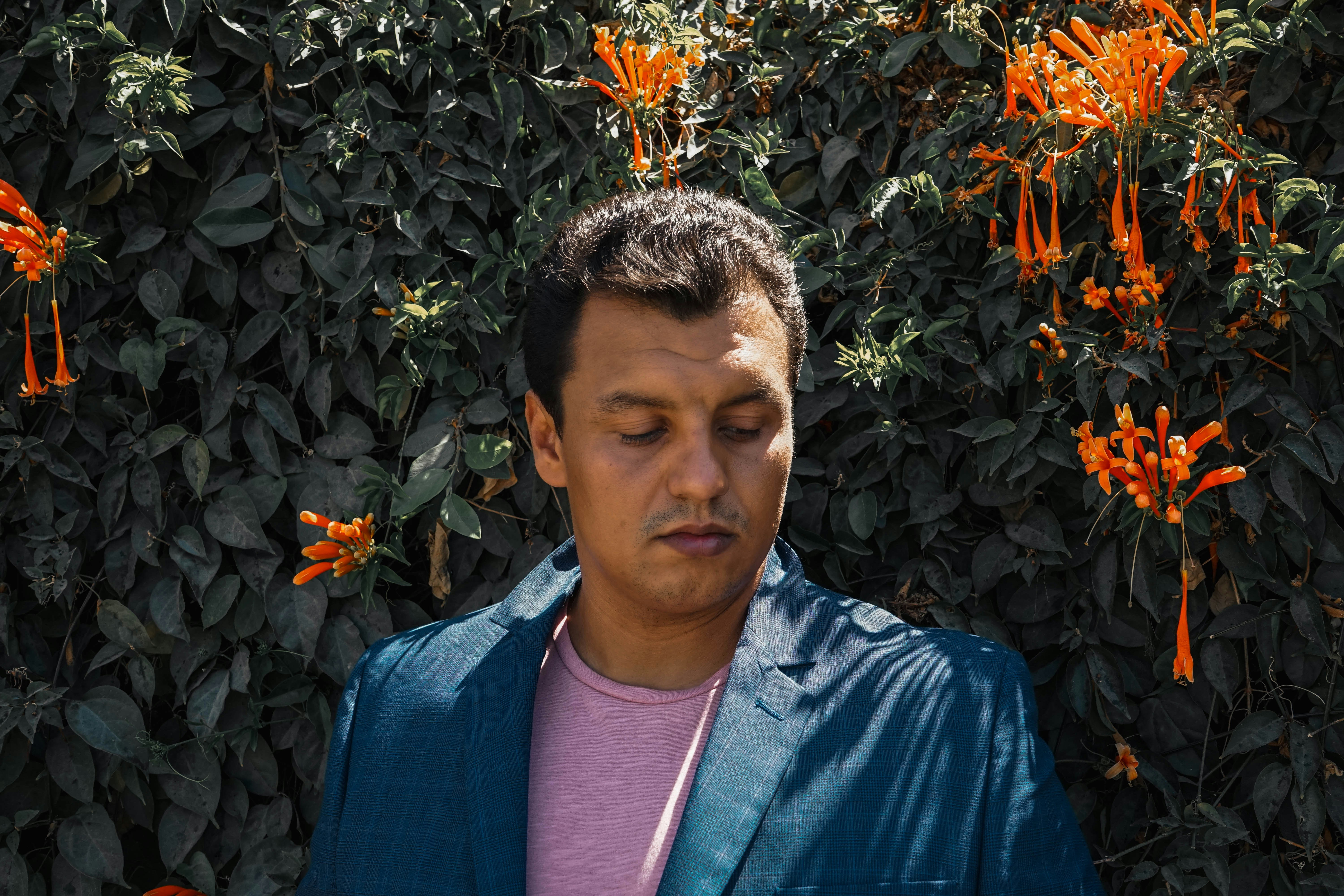 A man standing in front of a bush with orange flowers