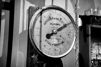 A barometer hanging on a wall next to a shelf