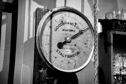 A barometer hanging on a wall next to a shelf
