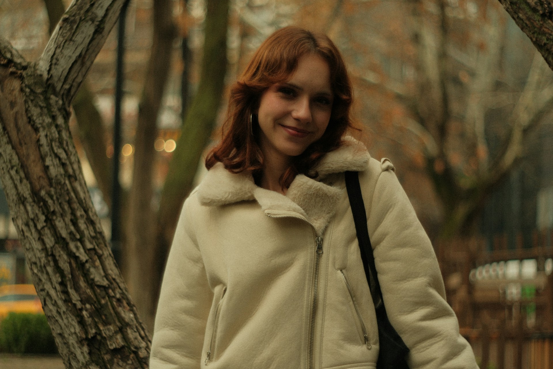 A woman in a white coat is walking down the street