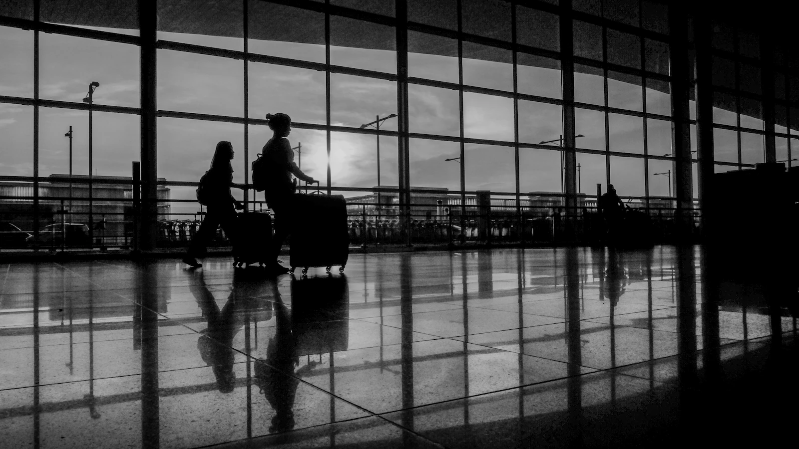 Travelers with luggage inside an airport, representing the practical realities of an international long-distance relationship