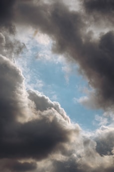 A plane flying through a cloudy blue sky