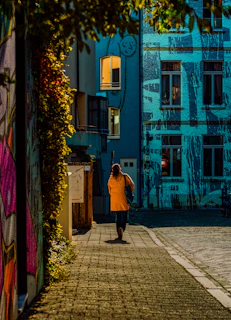 A man walking down a street next to tall buildings
