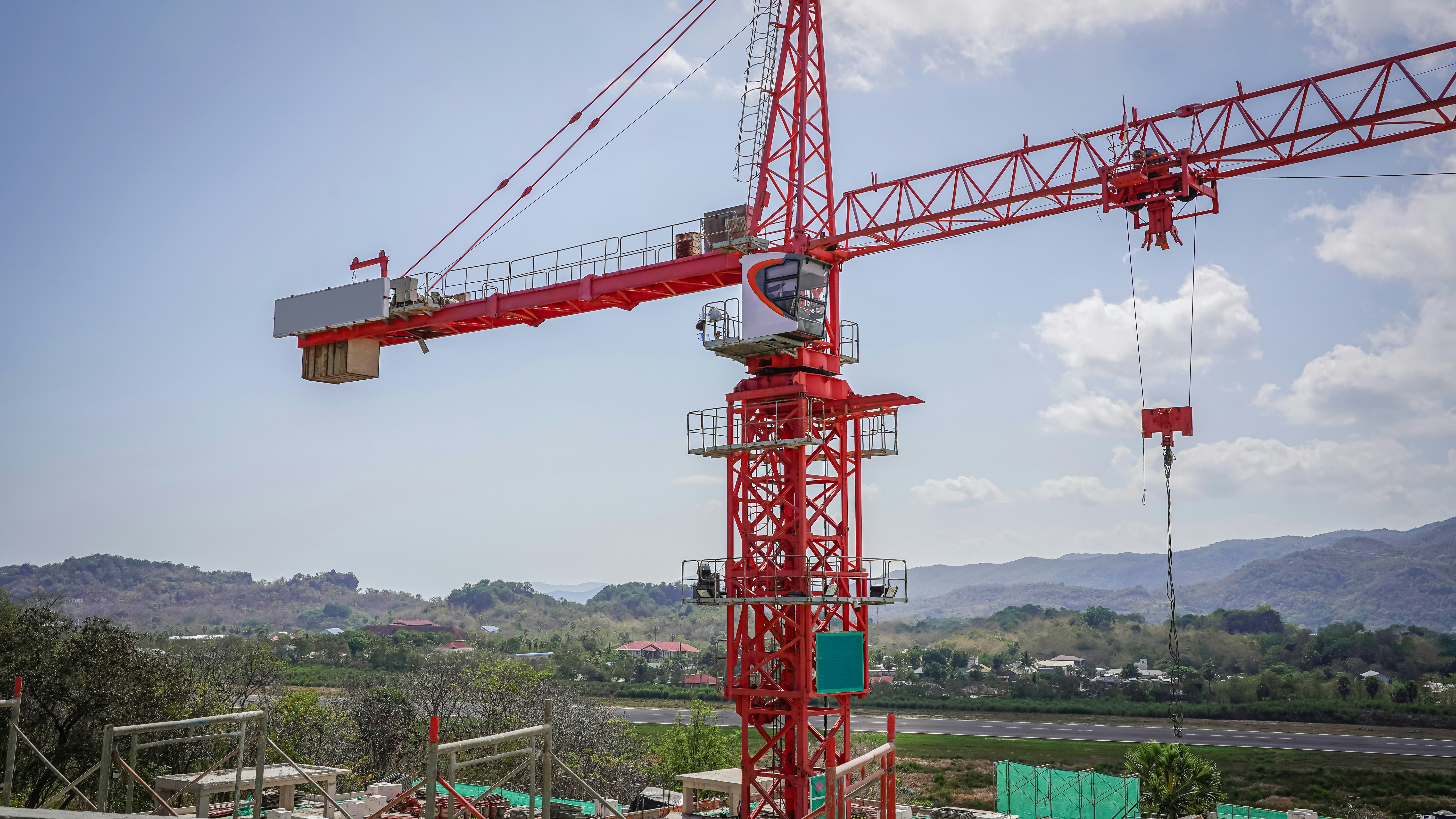 A red crane is standing in the middle of a construction site