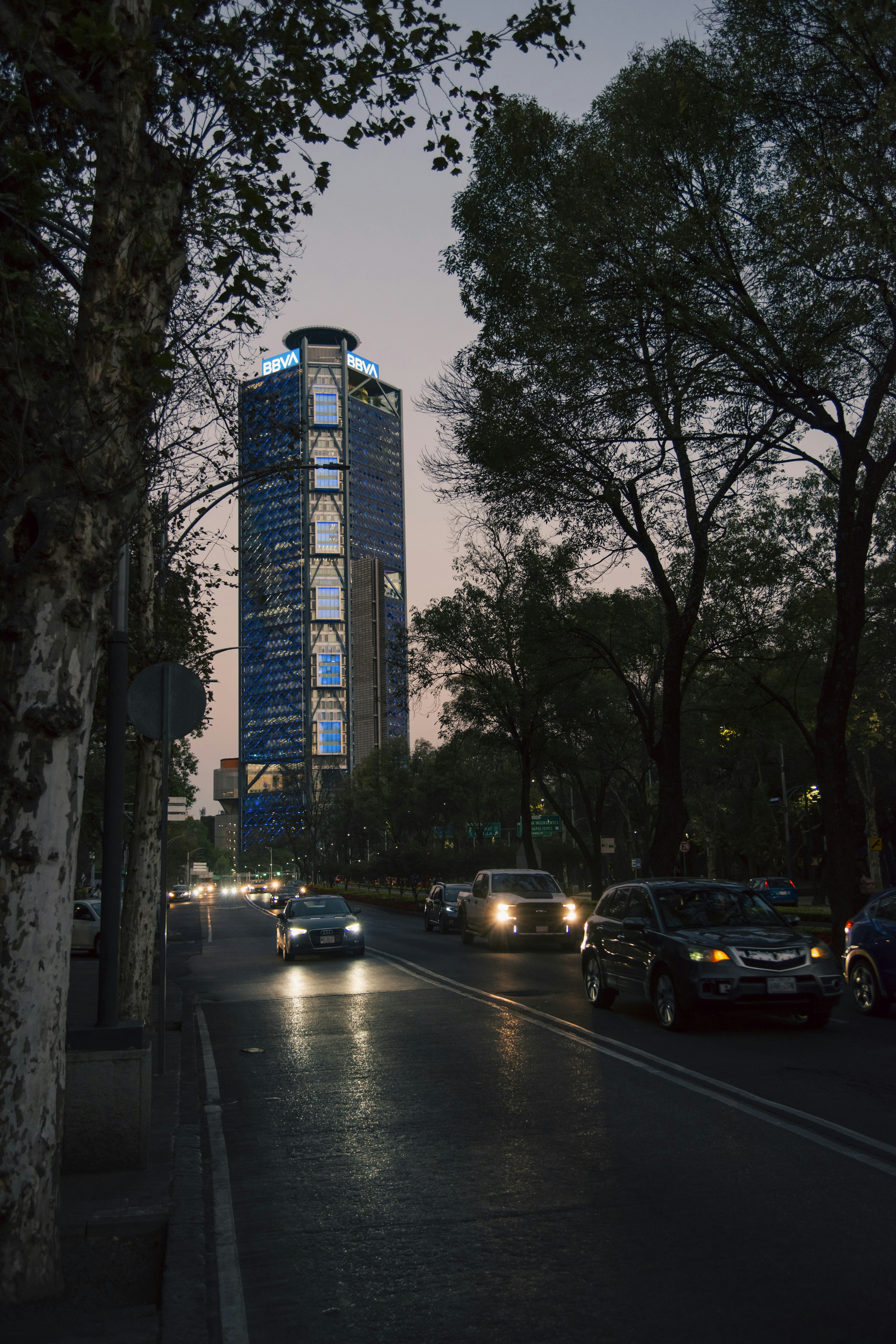 A city street at night with a tall building in the background