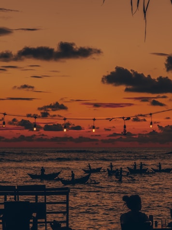 A group of people sitting on a dock watching the sunset