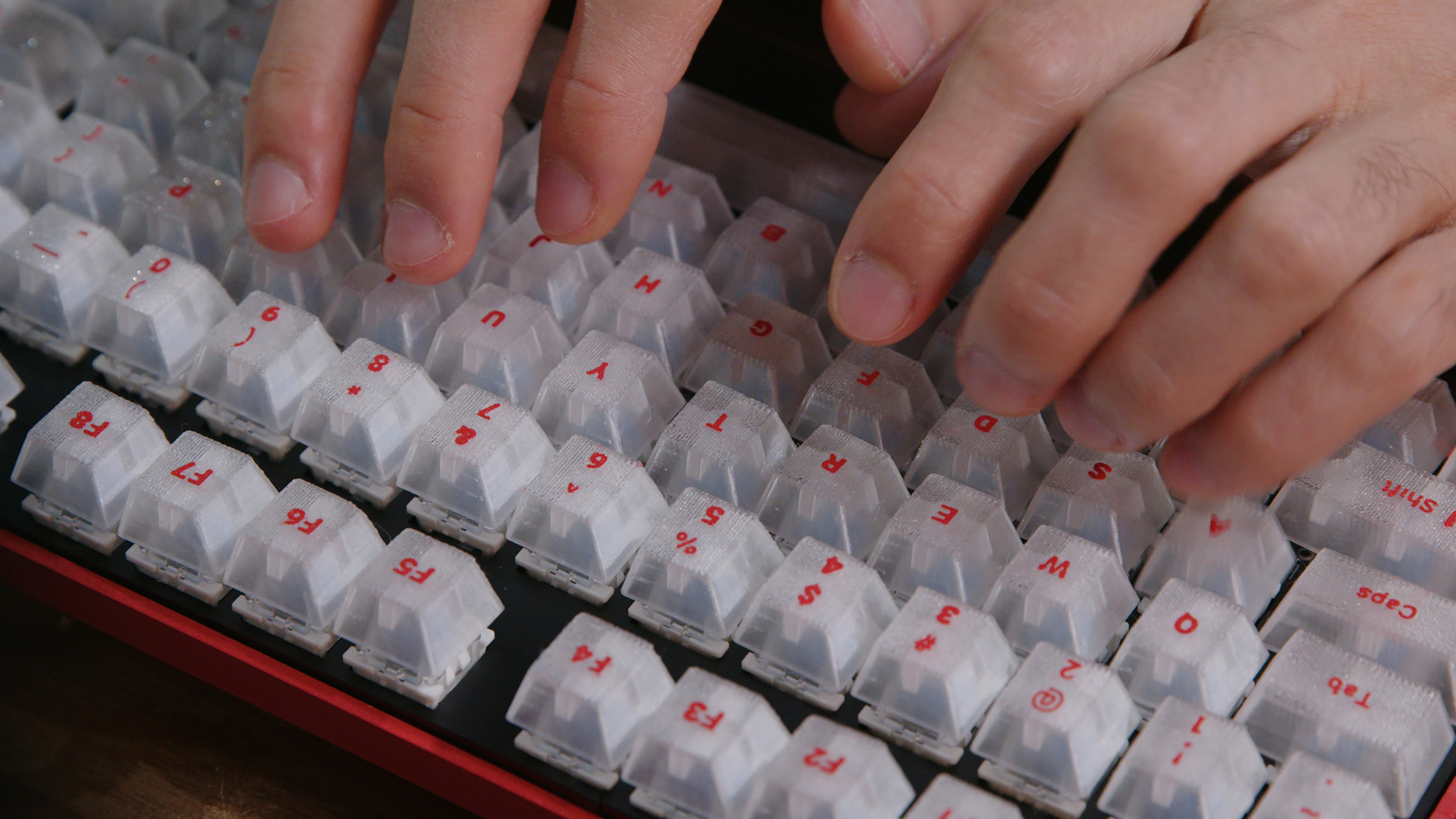 A close-up shot of a person typing on a keyboard, showcasing a 3D-printed mechanical keyboard.