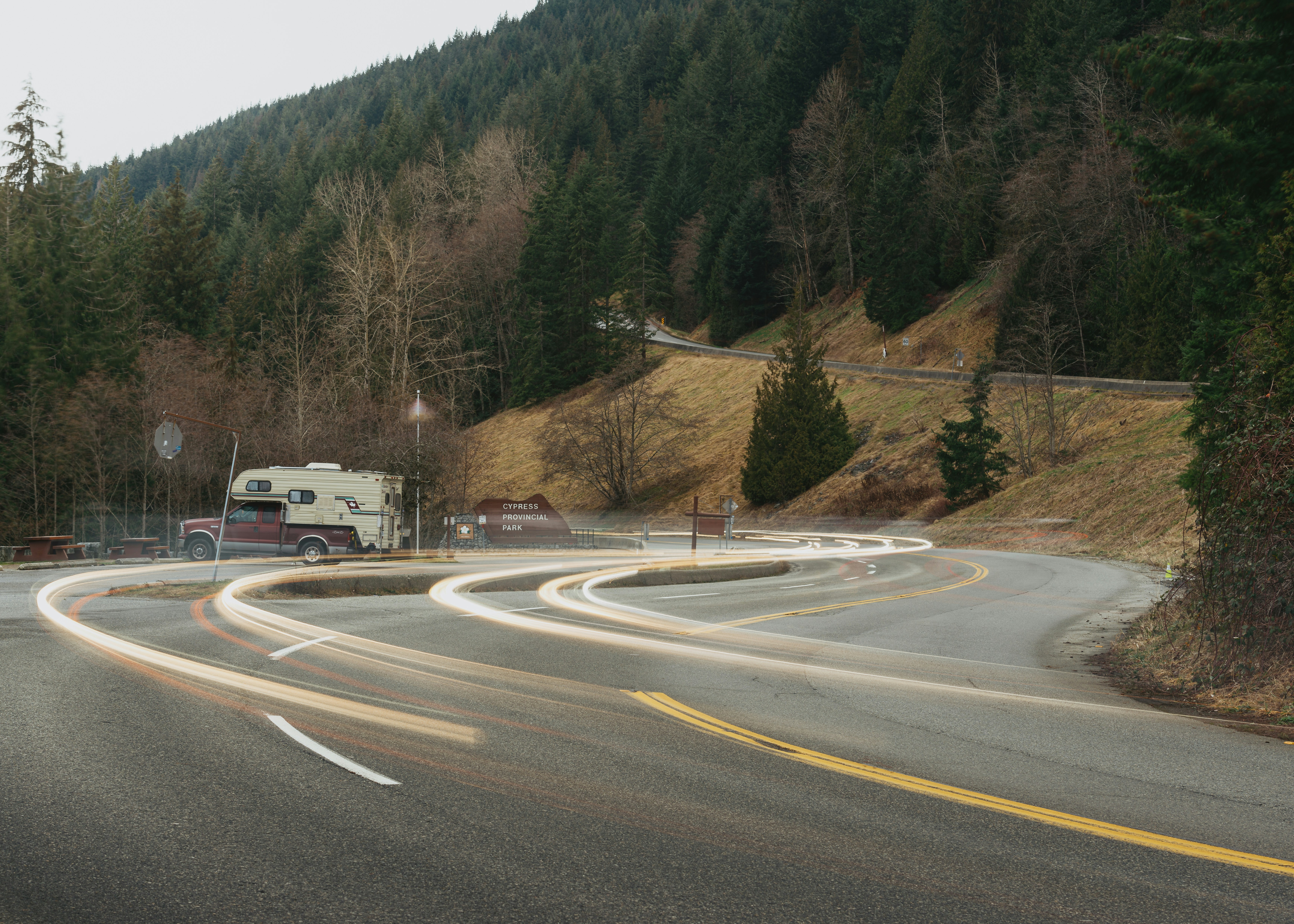 A truck driving down a curvy road next to a forest