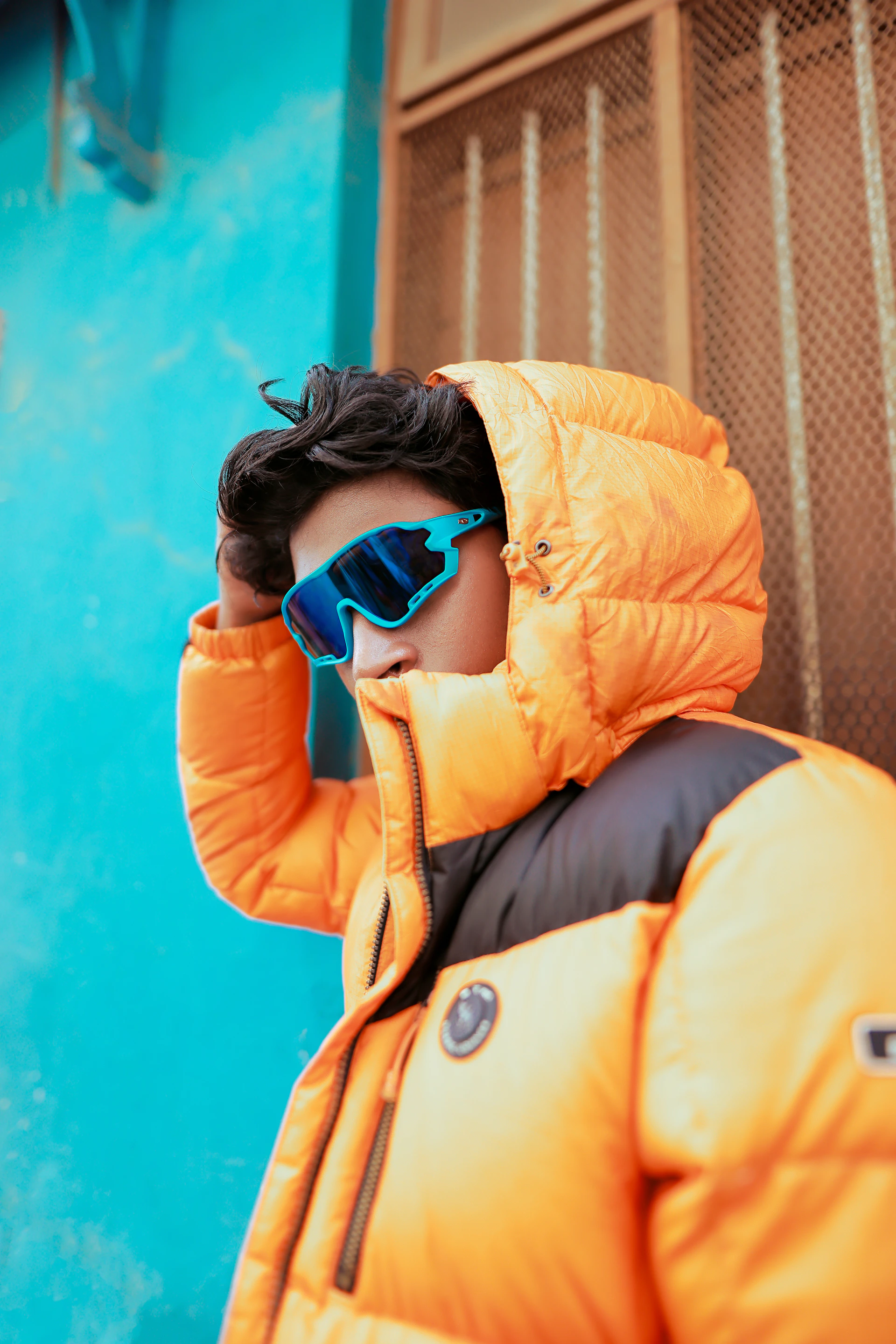 A young man wearing a yellow jacket and blue sunglasses