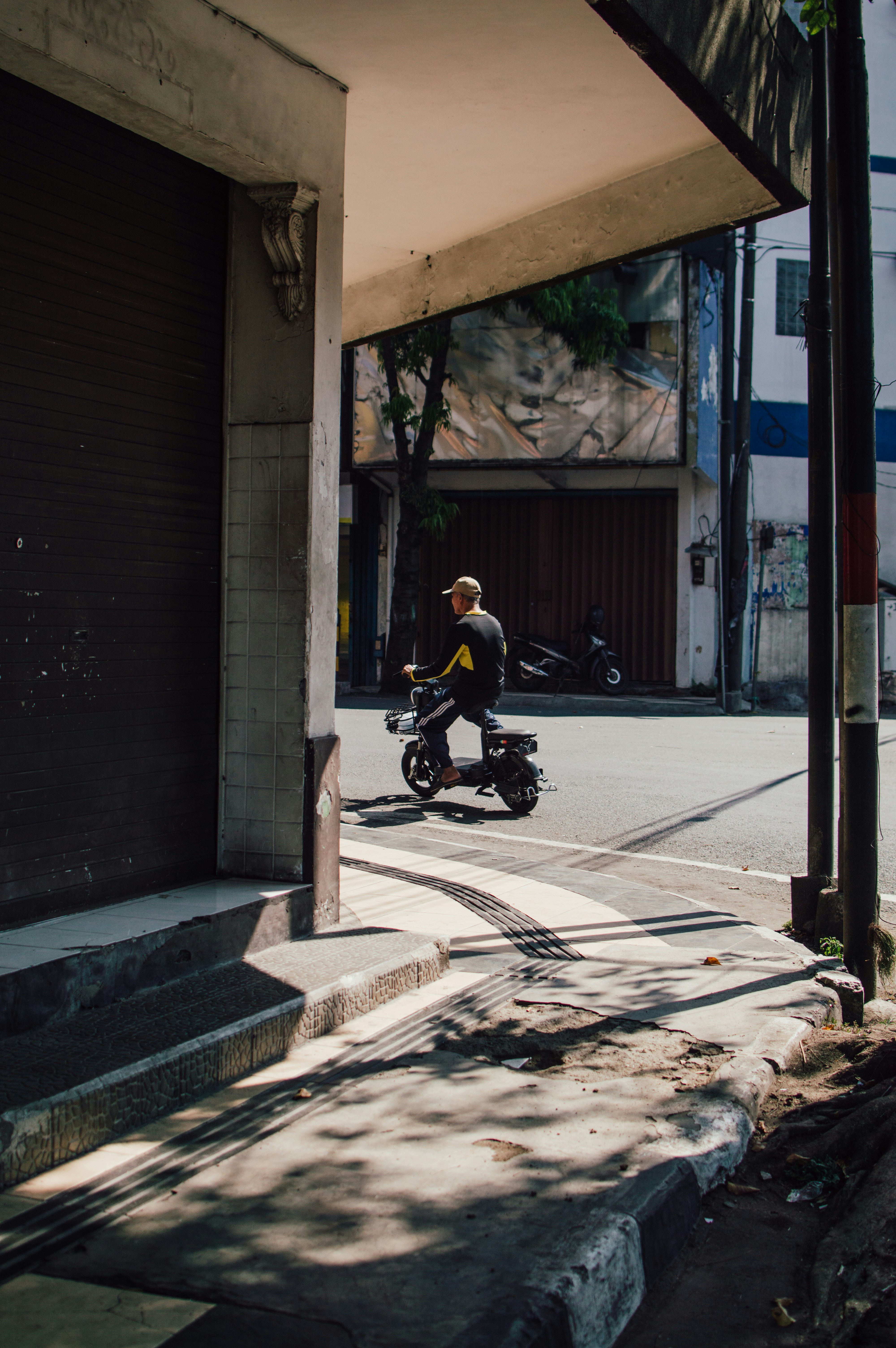 A man riding a motorcycle down a street next to a tall building