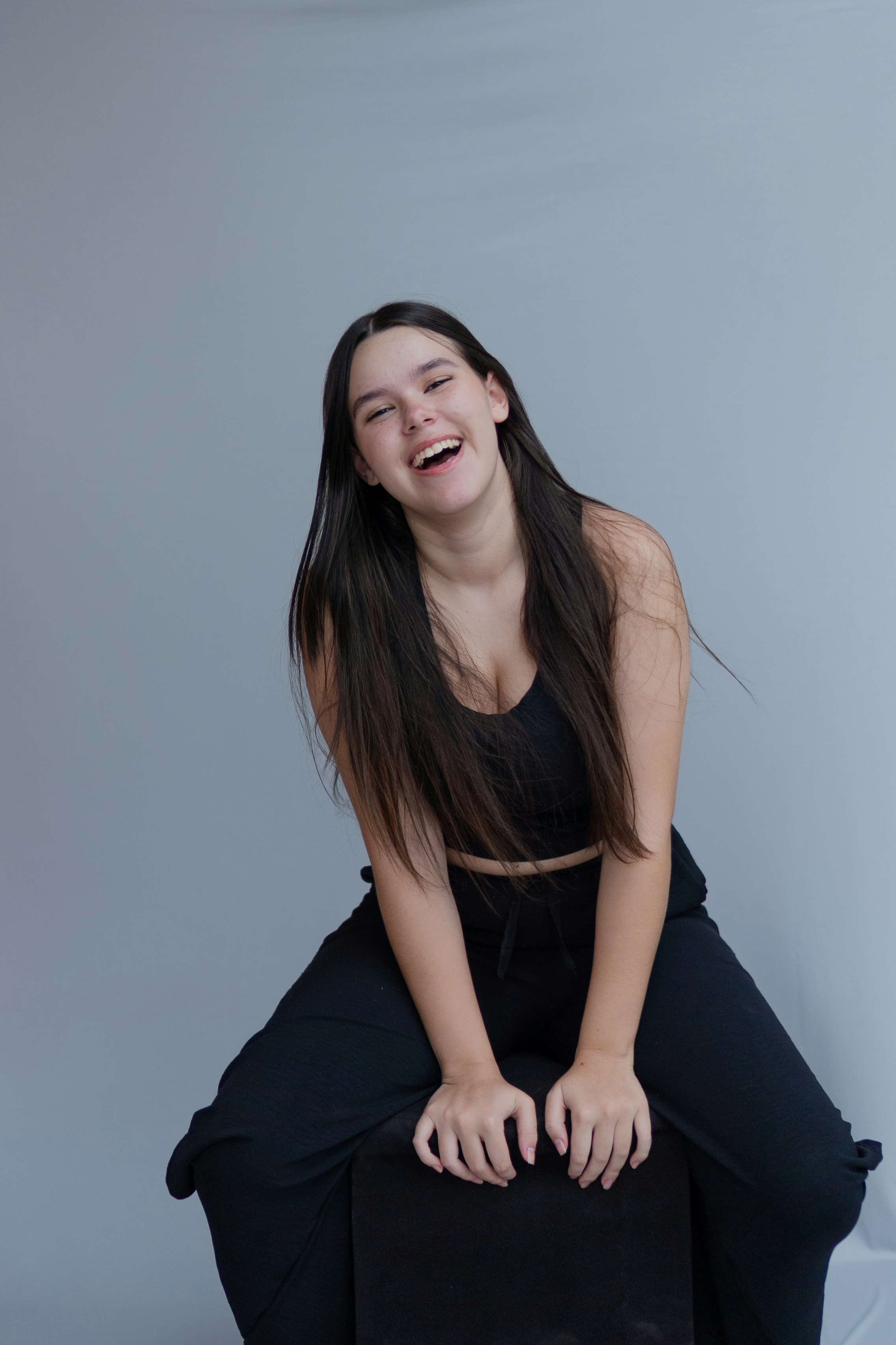 A woman sitting on top of a black suitcase