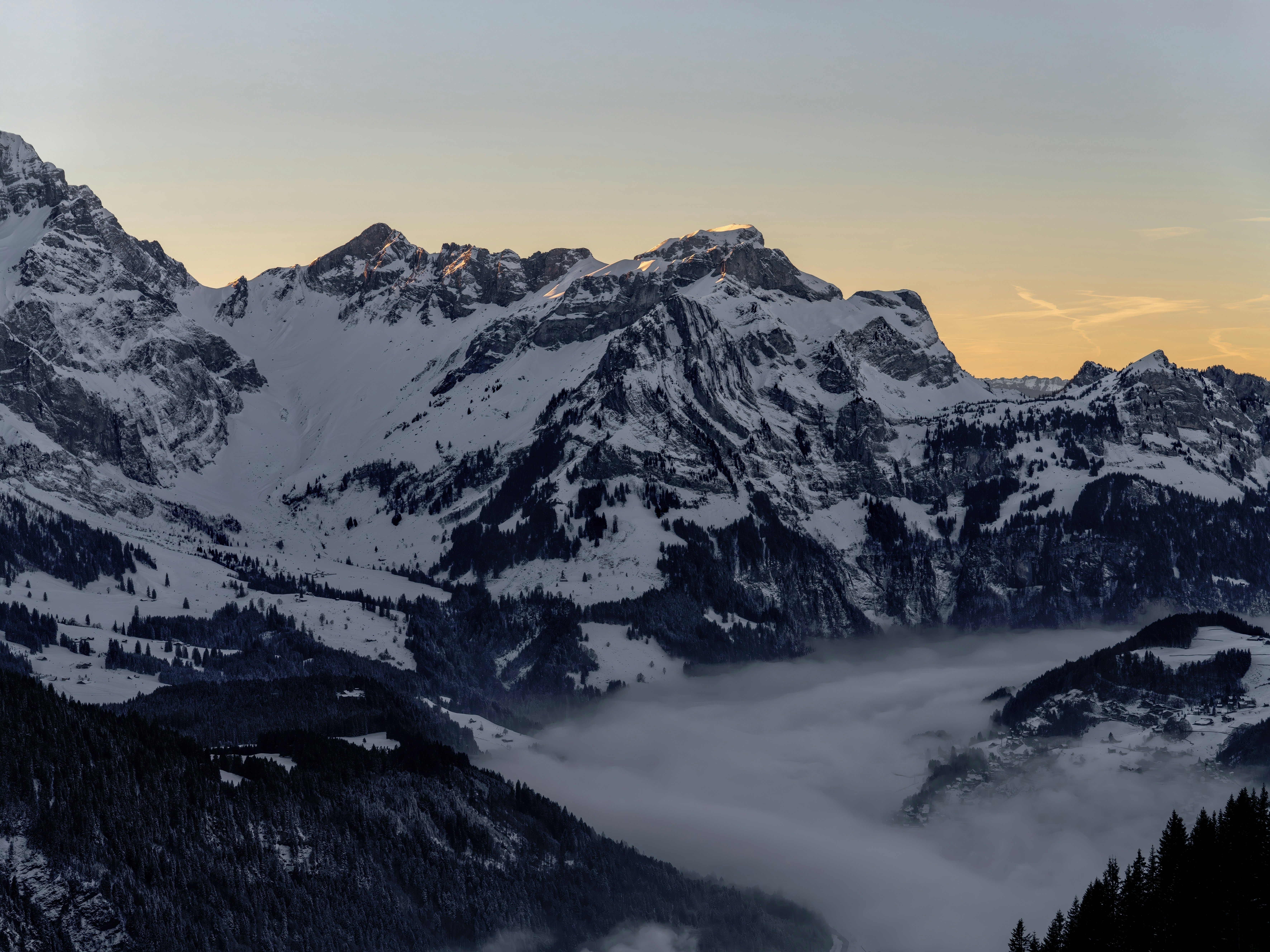 A mountain range covered in snow and clouds