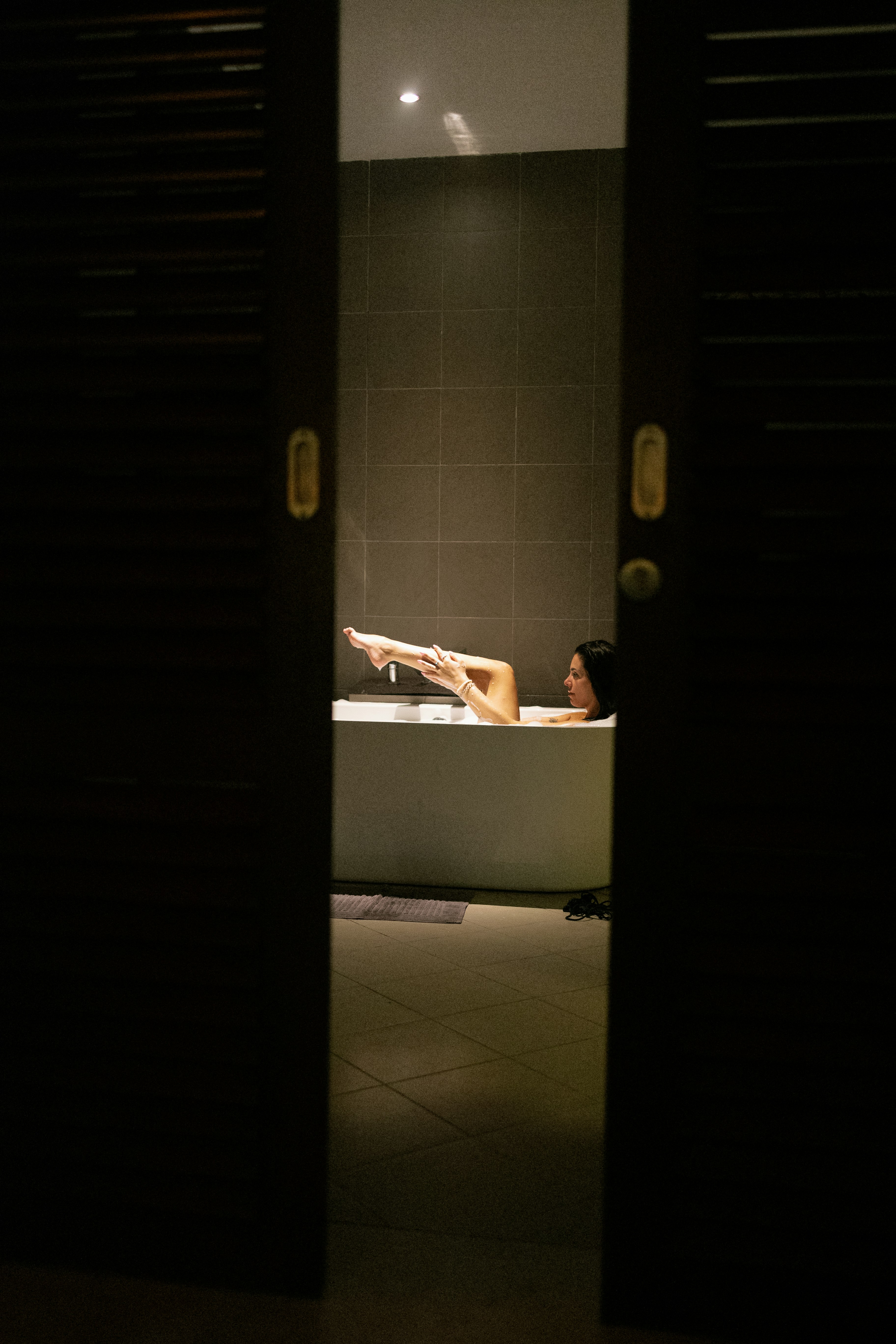 A woman laying in a bathtub in a dimly lit room