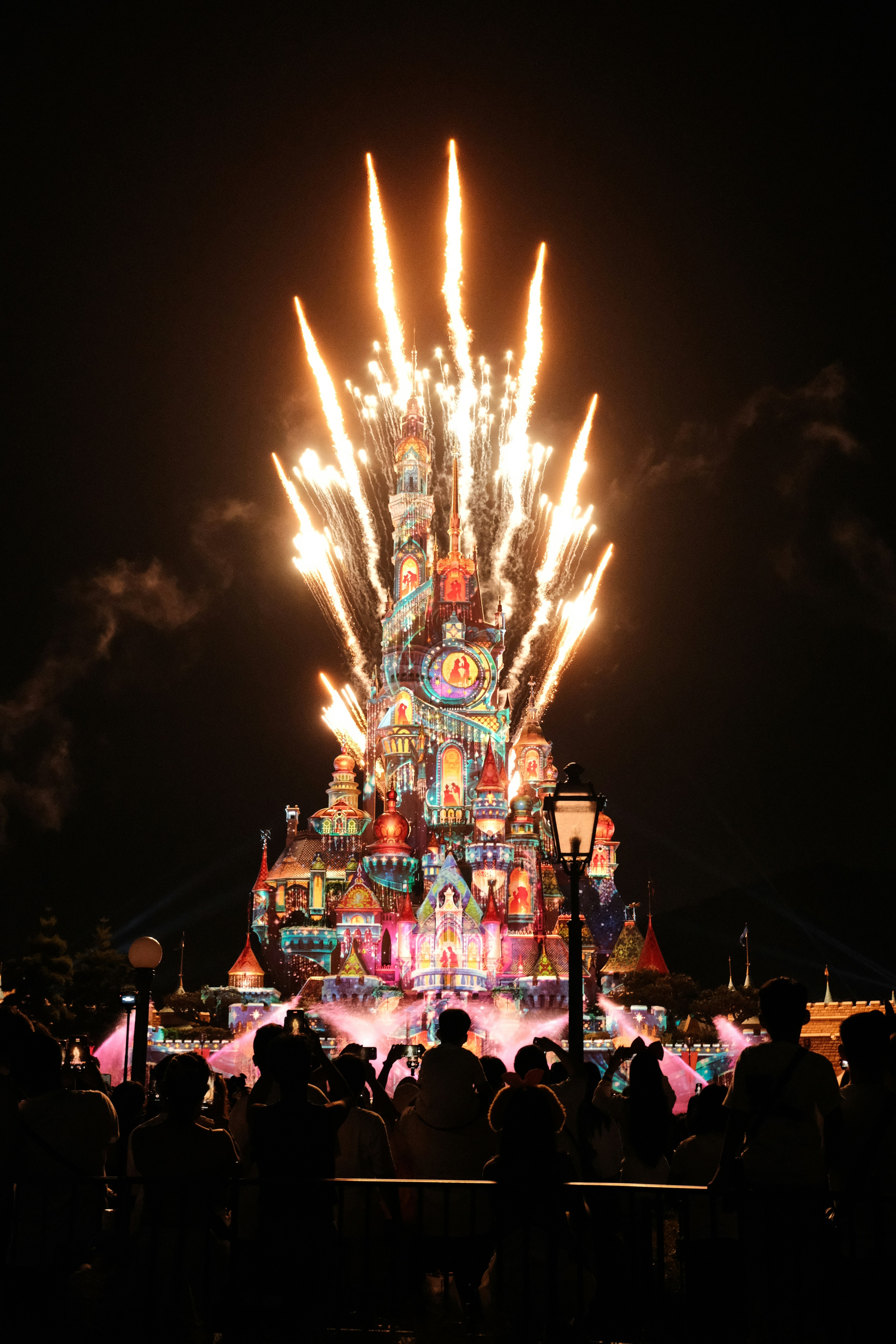 Una multitud de personas de pie alrededor de un castillo iluminado