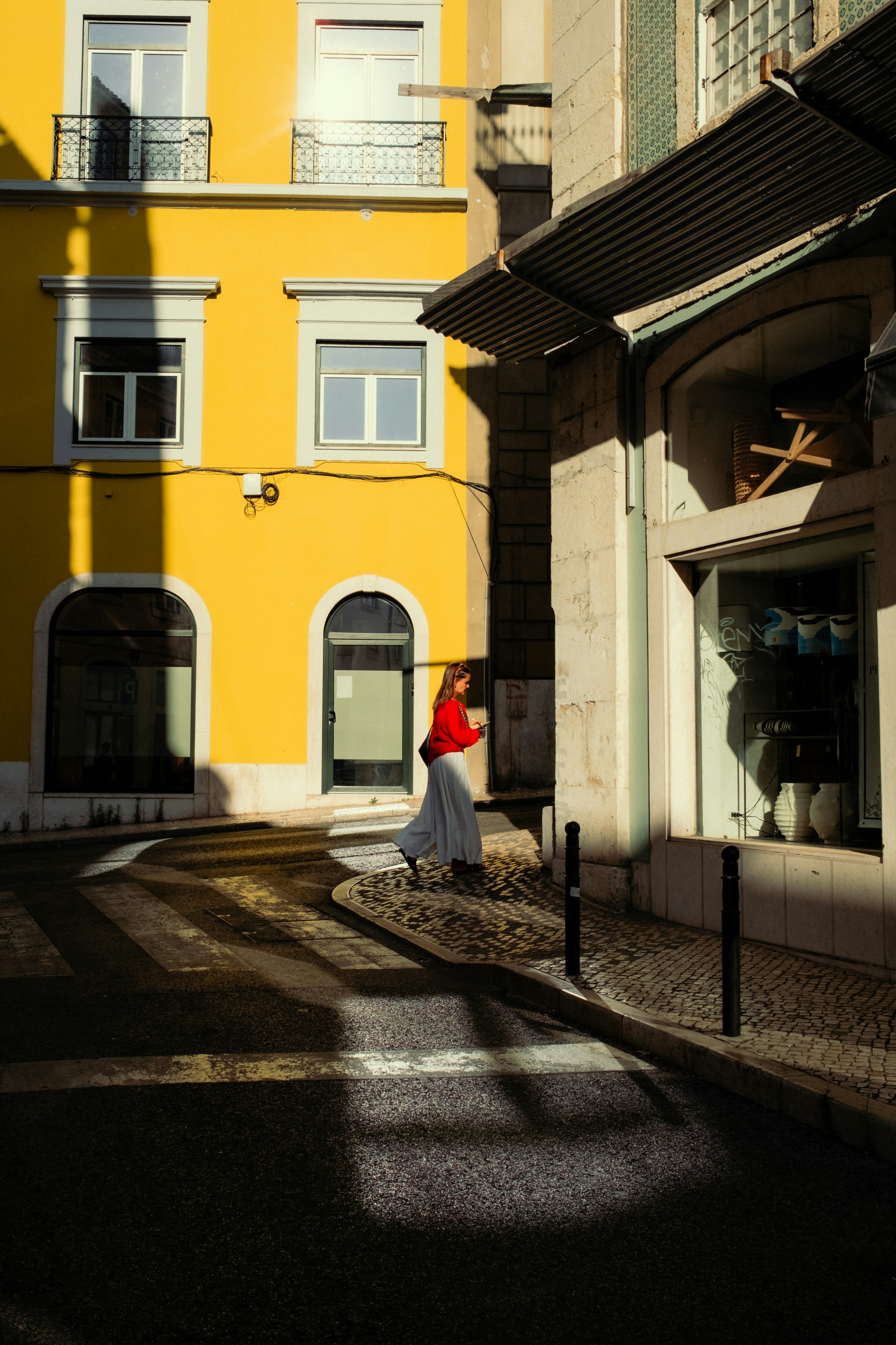 A woman walking down a street next to tall buildings