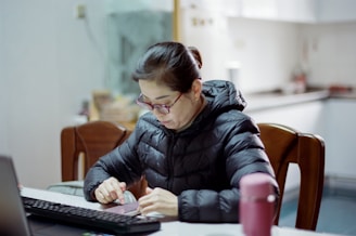 A woman sitting at a table working on a laptop