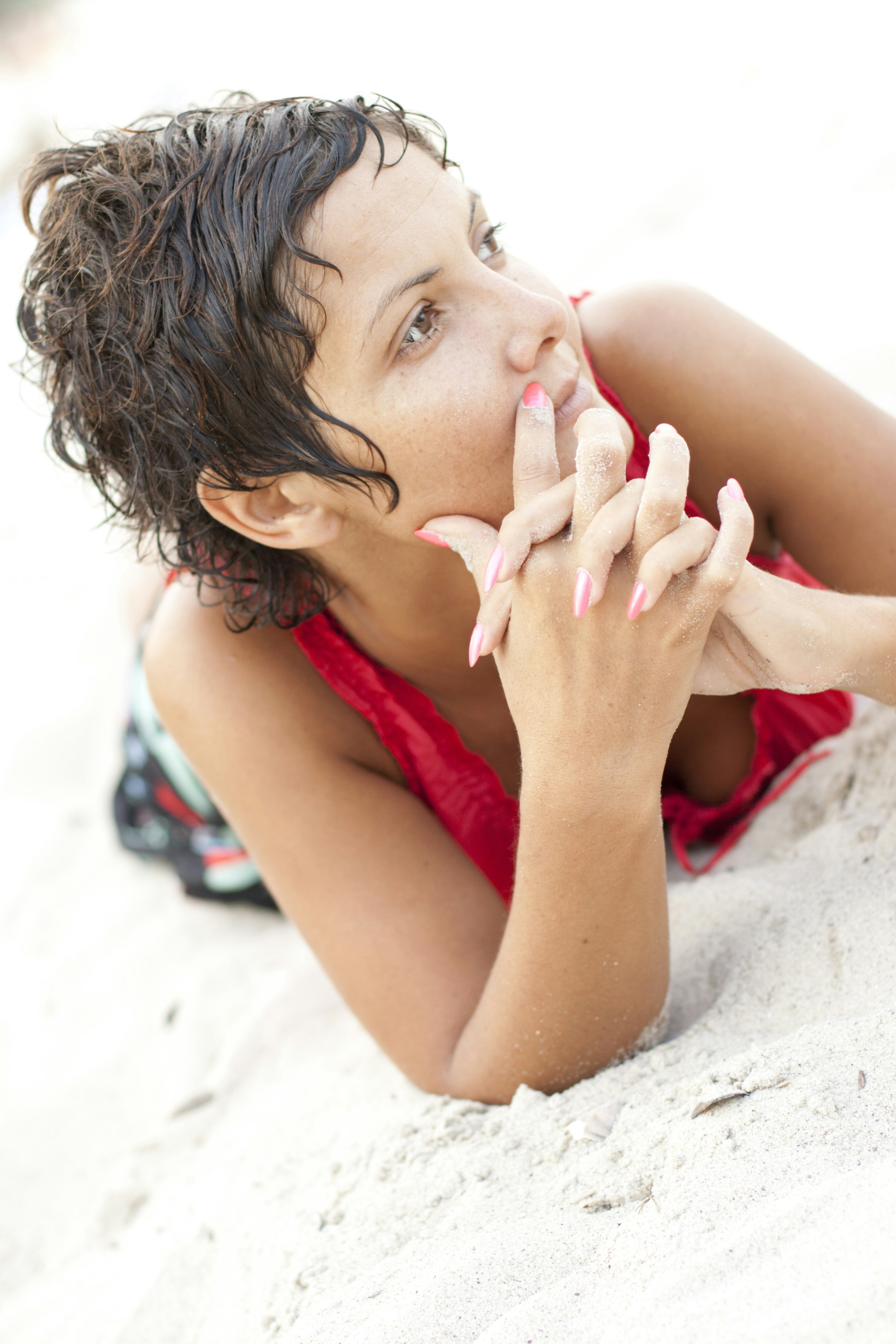 A woman laying in the sand with her hands on her face photo – Free Pink ...