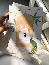 A person holding a card with a peacock on it