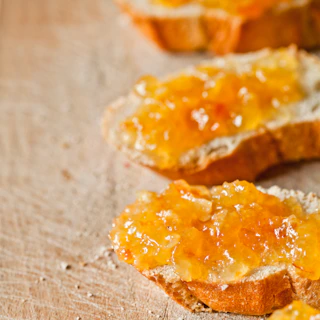 A piece of bread with orange marmalade spread on it