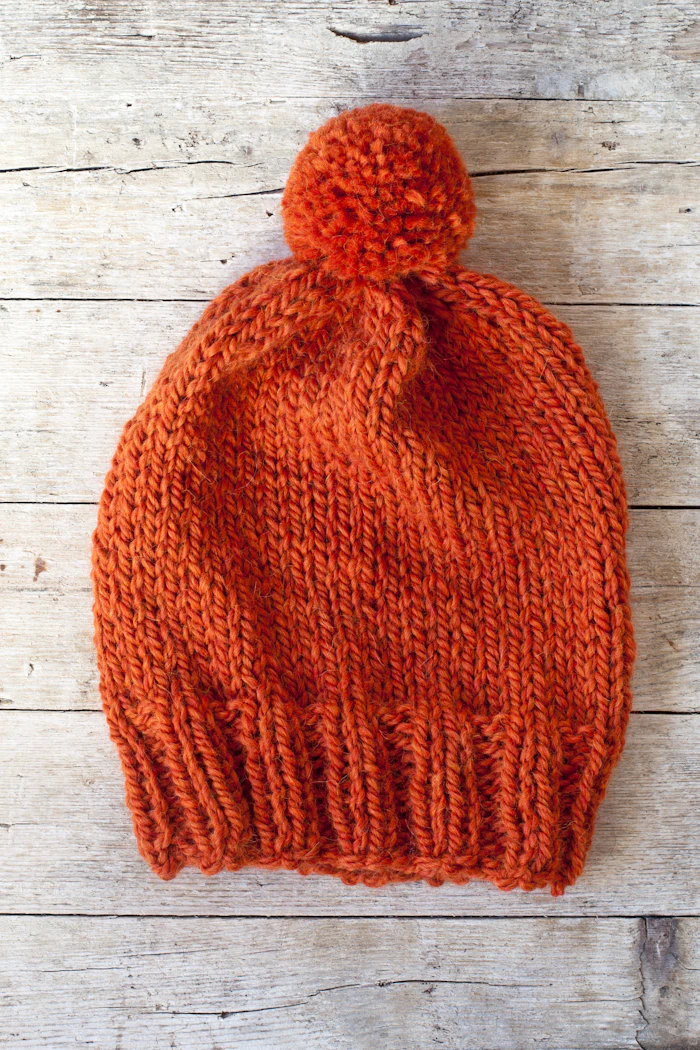 A cosy orange knitted hat with a pom-pom