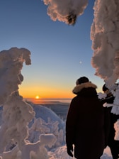 A couple of people standing on top of a snow covered slope