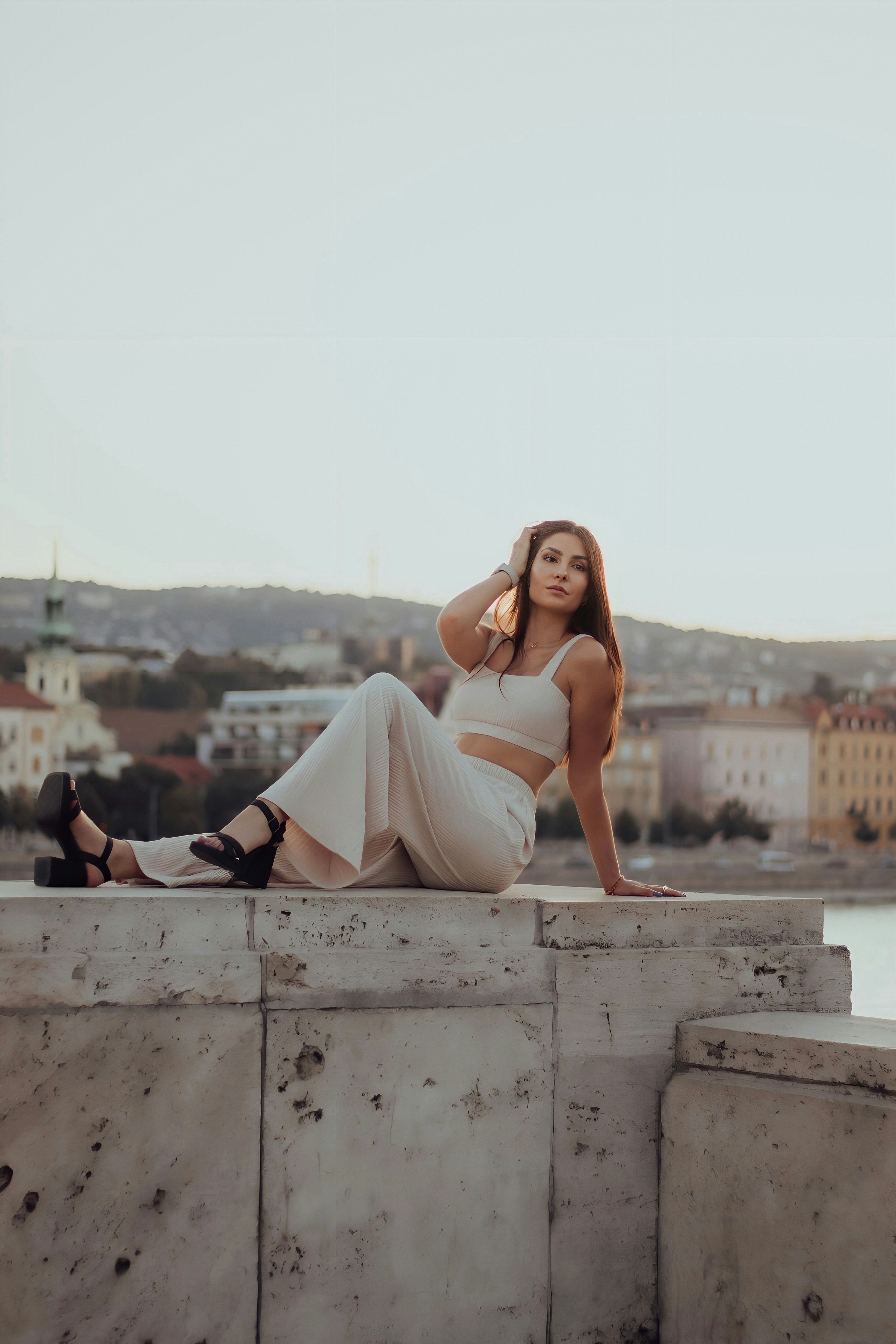 Una donna in un vestito bianco seduta su un muro